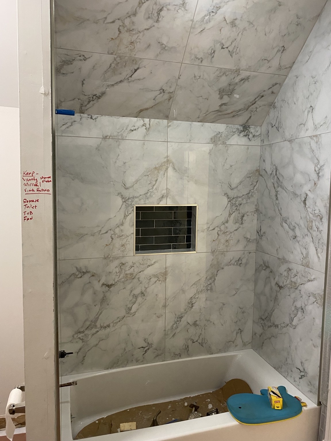 Marble-look tile tub surround with a dark tiled niche