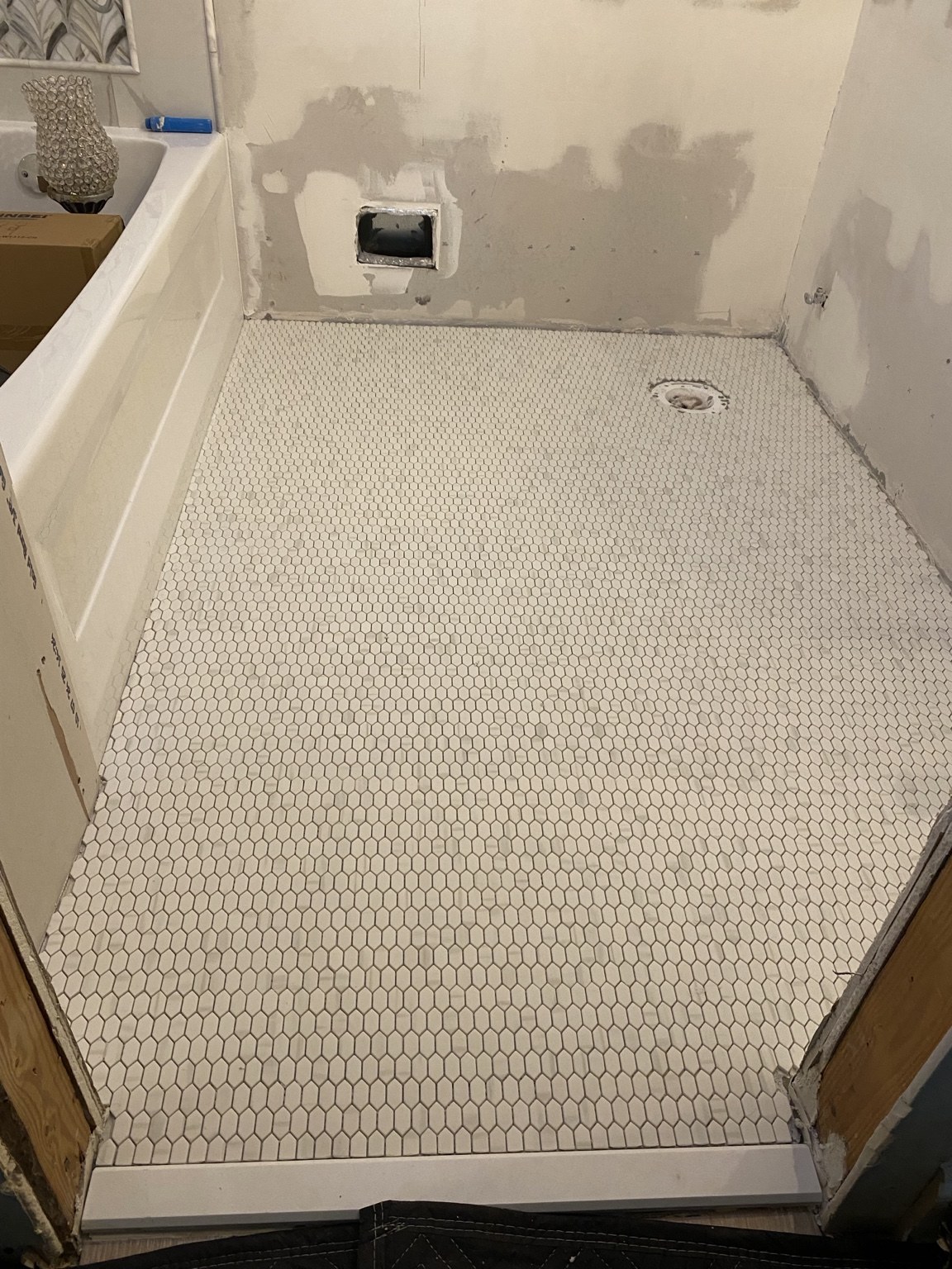 White hexagonal mosaic bathroom floor during installation