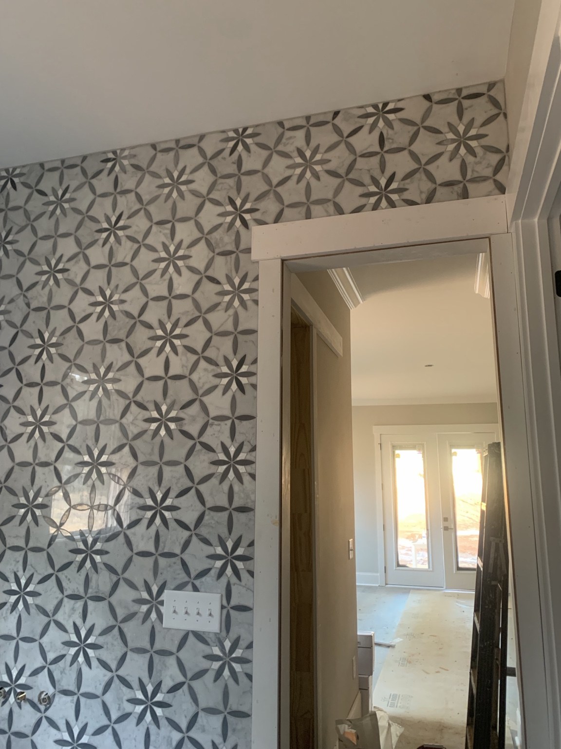 Floral-pattern tile wall around a bathroom doorway during installation