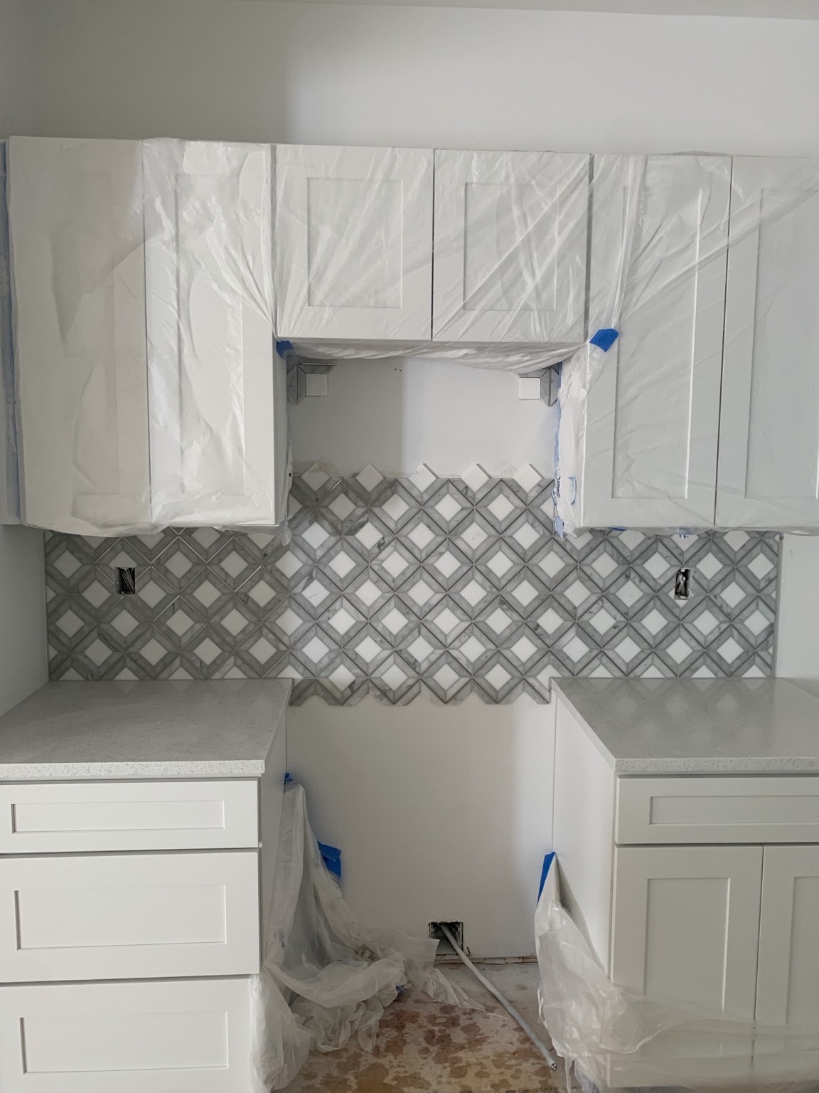 Gray and white diamond-pattern kitchen backsplash during installation